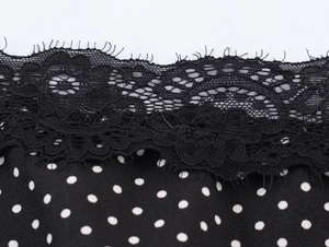 Detailed macro view of black polka dot fabric with intricate black lace trim stitching