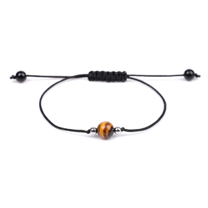 Handmade woven bracelet featuring a natural tiger eye bead and adjustable cord closure