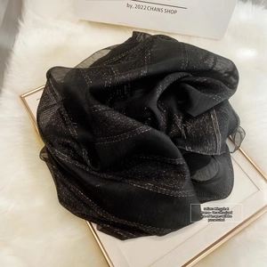Detailed texture of black silk wool scarf with metallic gold stripes on white fur