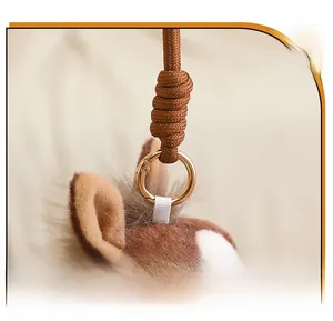 Detail of plush pony keychain featuring a brown woven strap and golden metal clasp ring