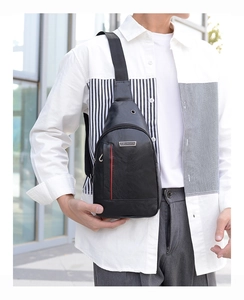 Close-up of black PU leather chest bag with red stripe and JINGPIN logo on model outdoors