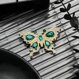 Vintage gold butterfly brooch with emerald green gemstones and sparkling rhinestones