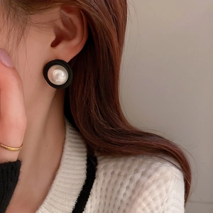 Vue détaillée de boucles d'oreilles vintage en acrylique avec perle blanche et bord noir