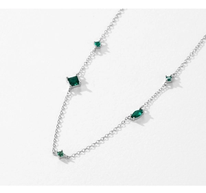 Detail of silver chain necklace with emerald green multi-shape gemstones in white background
