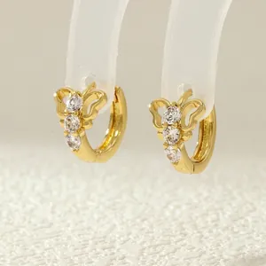 Macro shot of 18K gold bow butterfly earrings with cubic zirconia on clear stand