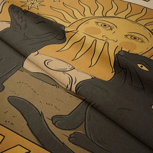Close-up of bohemian tapestry fabric showing two black cats and sun pattern texture