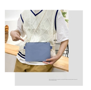Close-up of a light blue nylon crossbody bag with woven shoulder strap detail
