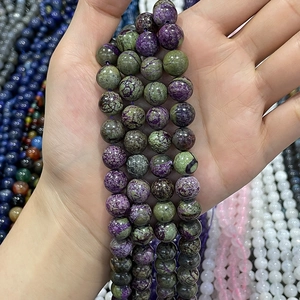 Handheld view of natural purple and green Stichtite round beads with marble texture