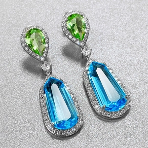 Macro detail of pear-cut green and blue sea blue zircon earrings with pave diamonds