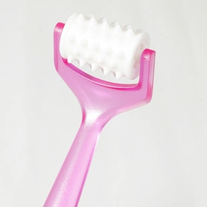 Close-up of pink handheld roller massager with white textured head for meridian facial care