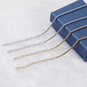 Golden and silver titanium steel box link necklaces with extension chains on a jewelry box