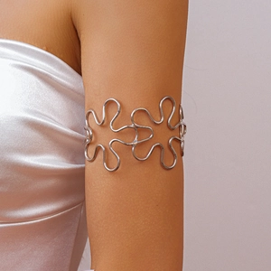 Close-up of a silver hollow floral cuff bracelet worn on the upper arm with wavy patterns