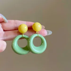 Vue détaillée de boucles d'oreilles rétro en résine avec perle jaune et anneau vert