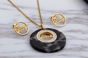 Detail of gold necklace and earrings set with tortoiseshell resin and love engraving