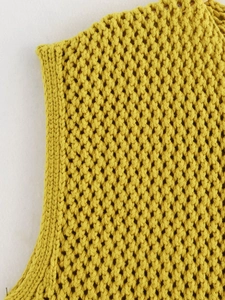 Dettaglio ravvicinato della trama a nido d'ape di un gilet in maglia gialla senza maniche