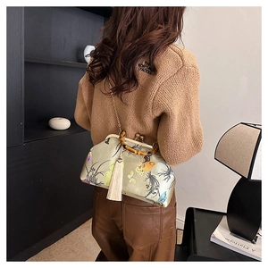 Detail of green silk handbag with floral embroidery, bamboo handle and beige tassel