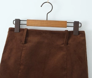 Detail of caramel corduroy skirt waist with belt loops on a wooden hanger