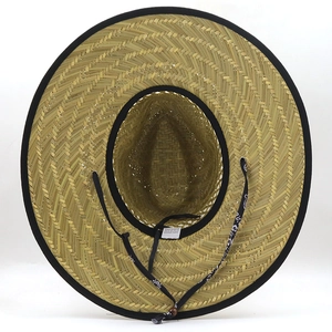 Vista dall'alto di un cappello di paglia naturale con trama in erba e laccetto stile boho