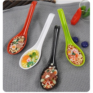 Macro shot of realistic ramen noodle soup miniatures in colorful long-handle spoons
