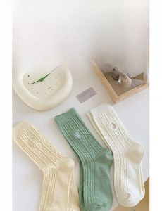 Détail de la texture tricotée et broderie sur chaussettes mi-hautes couleurs pastel