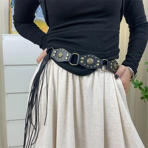 Detail view of black leather Y2K belt with brass rivets, metal rings and long tassels