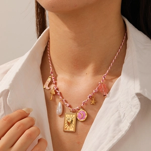 Detail of pink woven necklace with golden starfish, heart plate, and pearl pendants on a model