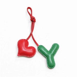 Detailed close-up of handmade red heart and green leather letter Y charms with stitching