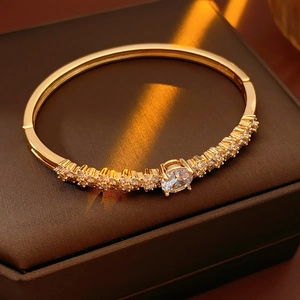 Detail of gold plated flower bangle with clear cubic zirconia on a luxury leather box