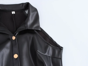 Detail of black faux leather dress showing turn-down collar and gold embossed buttons
