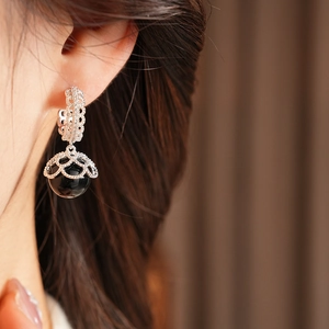 Detailed view of vintage gold plated earrings with black pearl and intricate metal carvings