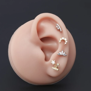 Primer plano de pendientes de luna y flores con circonitas en un modelo de oreja