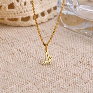 Detail of a gold letter A pendant with a small heart on a polished cable chain necklace