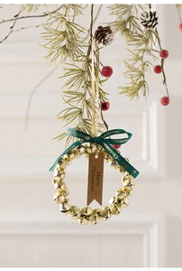Detailaufnahme goldener Weihnachtsglocken mit grüner Schleife und Merry Christmas Tag