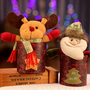 Detail of Santa and reindeer plush candy jars on a wooden crate with festive bokeh