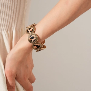Detailed close-up of bohemian gold leopard print disc bracelet on a model wrist