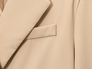 Detailed close-up of khaki woven fabric blazer showing lapel and pocket stitching
