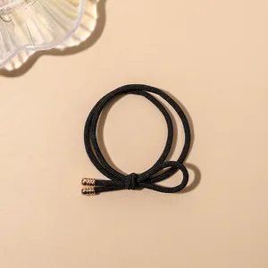 Detail of black double-layered braided hair tie featuring an elegant gold metal clasp