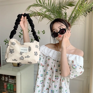 Close-up of butterfly embroidery on cream canvas tote bag with black scrunchie handle
