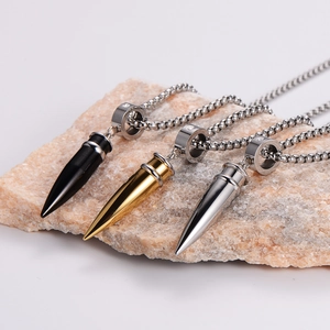 Three bullet pendant necklaces in black, gold, and silver on a textured stone base