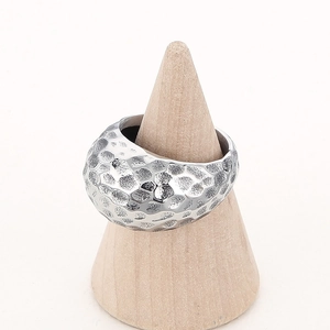Detailed close-up of a silver hammered texture steel ring on a wooden cone display