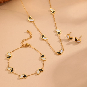 Chic gold titanium steel jewelry set with black and white heart motifs on peach background