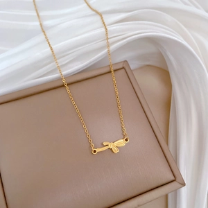 Close-up of gold bow pendant necklace on a jewelry box with elegant satin fabric