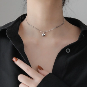 Minimalist silver lucky necklace featuring a spherical pendant with lucky engraving