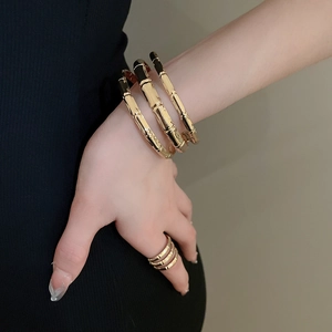 Detail of gold bamboo texture multi-layer bracelets and matching rings on model