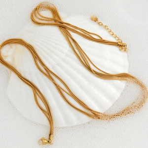 Multi-layer gold snake chain necklace displayed on shells for a modern luxury look
