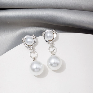 Macro detail of elegant silver earrings with white pearls and sparkling rhinestones