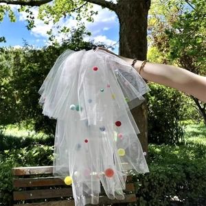 Close-up of white layered bridal veil featuring colorful pom-poms for wedding parties