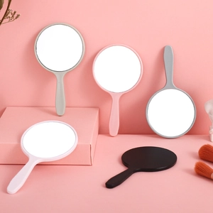 Mini hand-held makeup mirrors in assorted pastel colors on a pink background