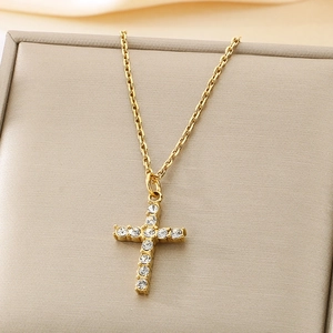 Macro shot of gold cross pendant with cubic zirconia stones and twisted chain texture