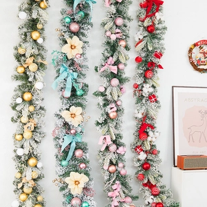 Guirlandes de Noël enneigées avec décorations dorées, bleues, roses et rouges au mur